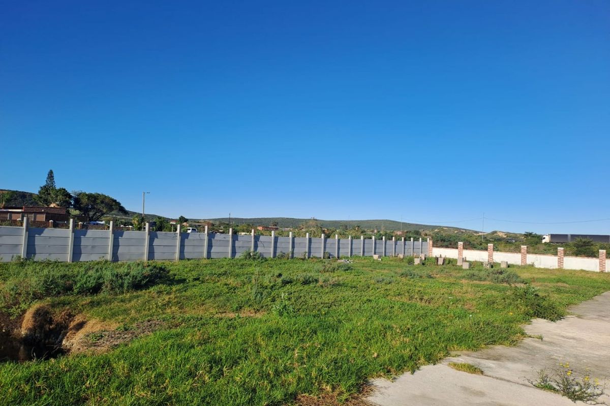 A vacant residential plot featuring a concrete driveway and a secure precast concrete boundary wall, offering a clear space for future development.