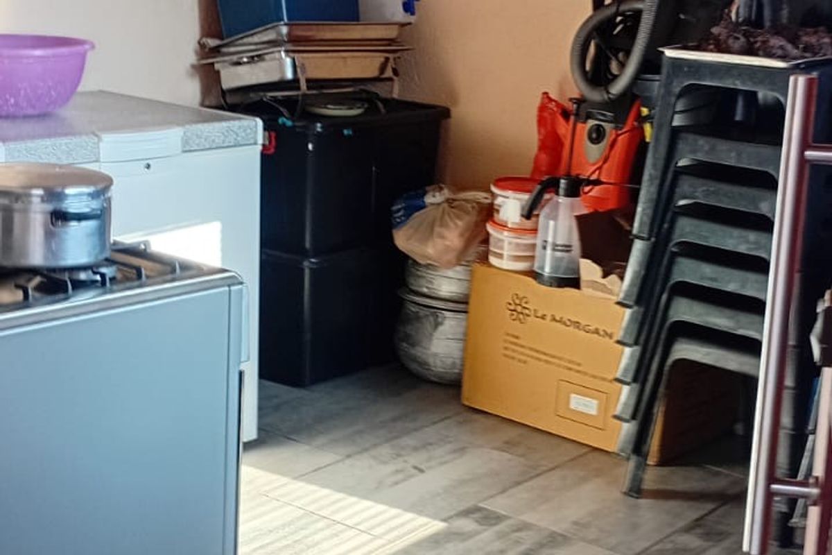 A functional kitchen area featuring modern grey tiled flooring and a freestanding stove, currently used for storage.