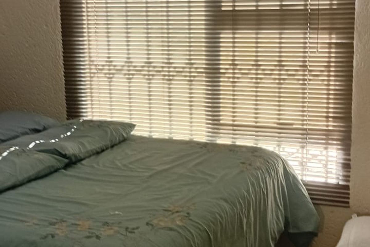 A bedroom featuring tiled flooring, cove cornicing, and fitted venetian blinds over the window.