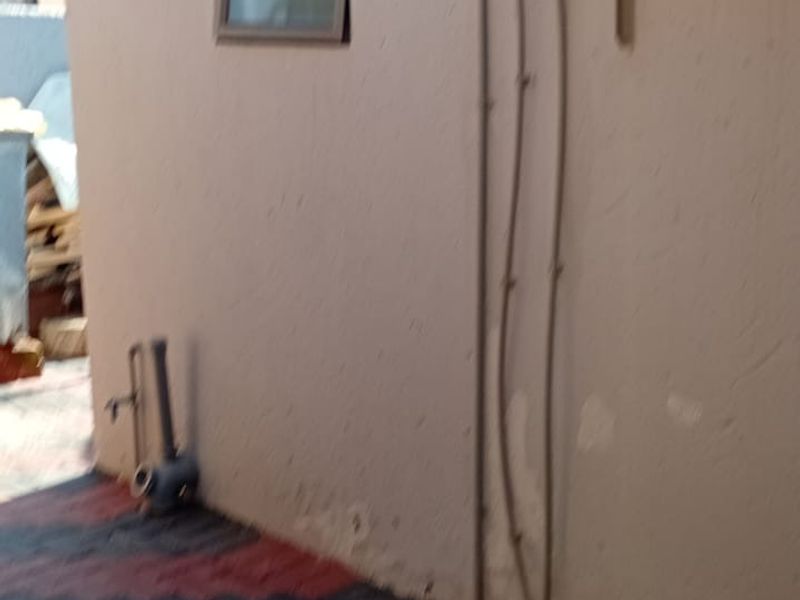 Rear exterior area featuring a solar water heater, external plumbing, and paved flooring.