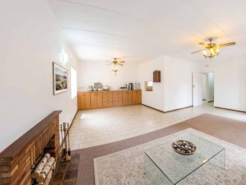 Spacious living area featuring a brick fireplace, built-in cabinetry, ceiling fans, and a combination of tiled and carpeted flooring.
