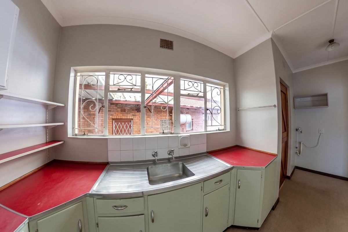 A functional kitchen area featuring fitted cabinetry, a stainless steel sink, and laminate countertops, offering a blank canvas for potential modern updates.