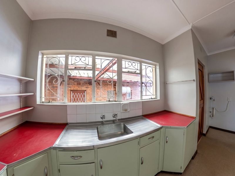 A functional kitchen area featuring fitted cabinetry, a stainless steel sink, and laminate countertops, offering a blank canvas for potential modern updates.