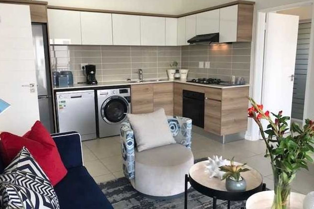 Modern open-plan kitchen featuring sleek wood-tone and white cabinetry, integrated appliances, tiled backsplash, and a functional layout flowing into the living area.