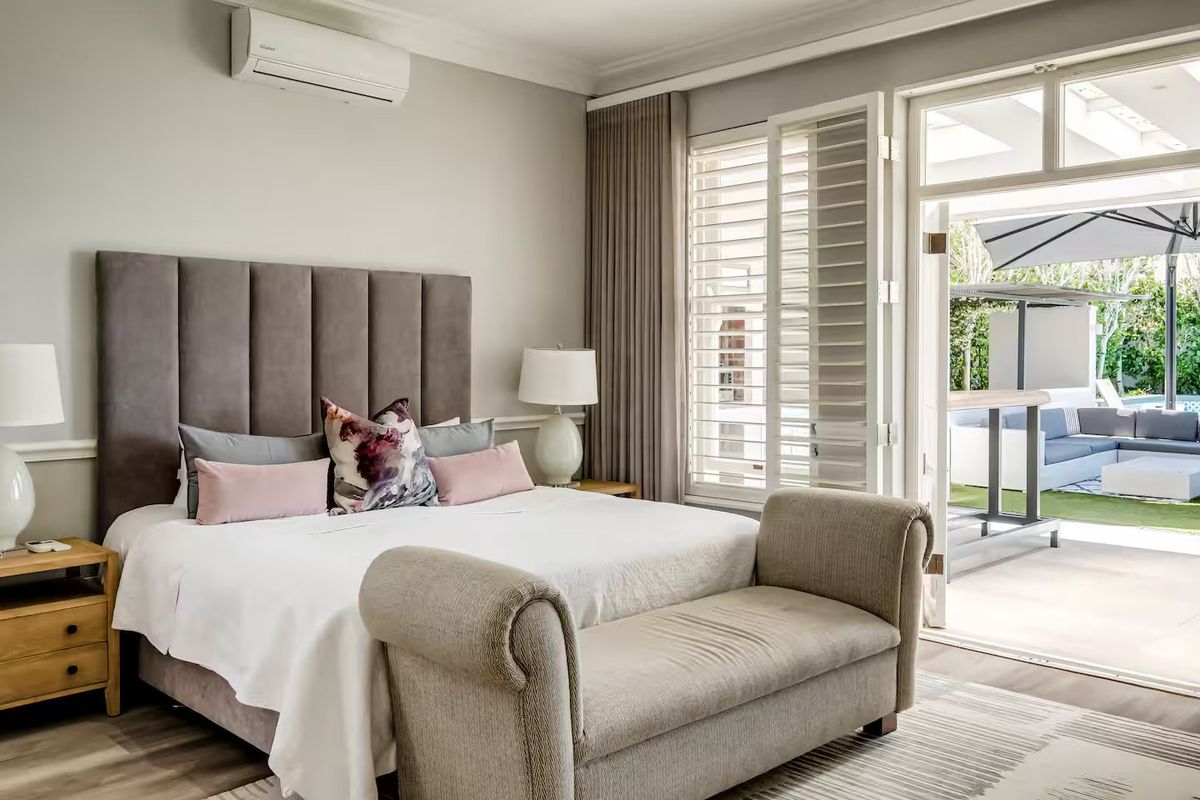 Spacious bedroom featuring elegant wainscoting, crown molding, plantation shutters, and direct access to a private patio through glass french doors.