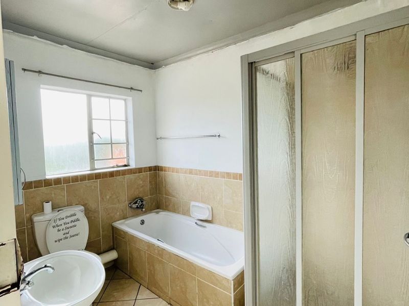 A dated bathroom featuring a pedestal basin, built-in bathtub, and a separate shower enclosure with tiled finishes throughout.