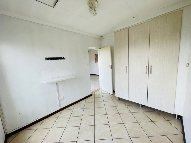 A vacant bedroom featuring tiled flooring and built-in cupboards, offering a blank canvas for personalization.