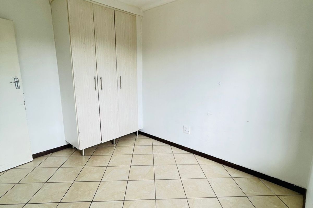 A vacant bedroom featuring neutral tiled flooring and a built-in wardrobe, providing a clean and functional space ready for personalization.