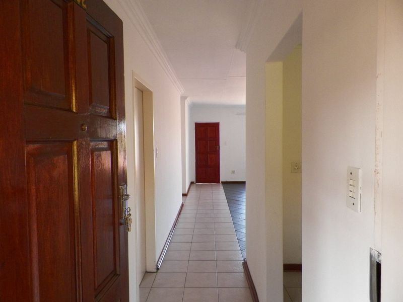 A functional hallway featuring tiled flooring, coving, and wooden doors, providing access to various rooms within the apartment.