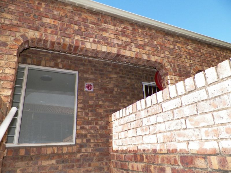 Exterior view of the apartment facade featuring face brick construction, arched architectural detailing, and security fixtures.