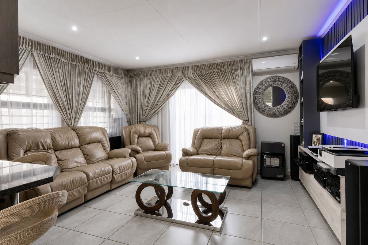 A well-maintained living room featuring tiled flooring, recessed downlighting, a split-system air conditioner, and a modern built-in media wall unit.