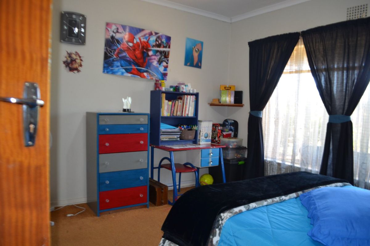 A standard bedroom featuring carpeted flooring and window treatments, providing a functional space for rest or study.