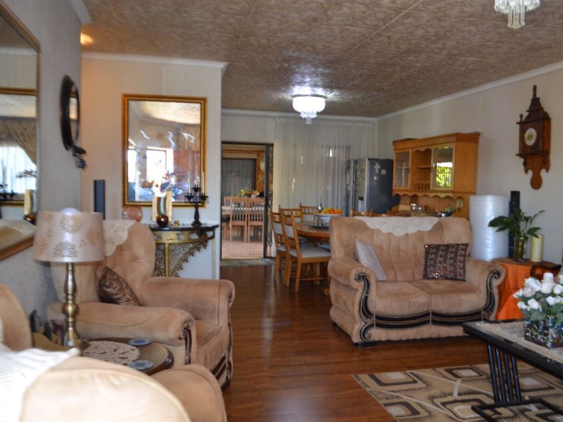 Spacious open-plan living and dining area featuring laminate flooring and a textured ceiling, providing a functional layout for family living.