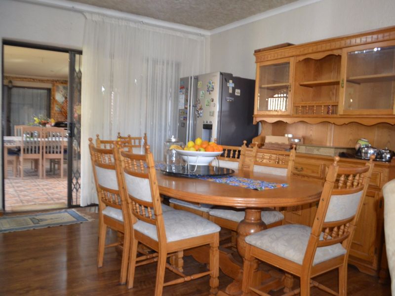 A traditional dining room featuring laminate flooring, coved ceilings, and a sliding glass door providing access to an adjacent room.
