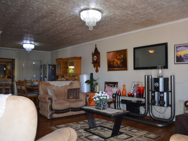 Open plan living and dining area featuring textured ceilings, dual chandeliers, and laminate flooring, providing a functional and connected living space.