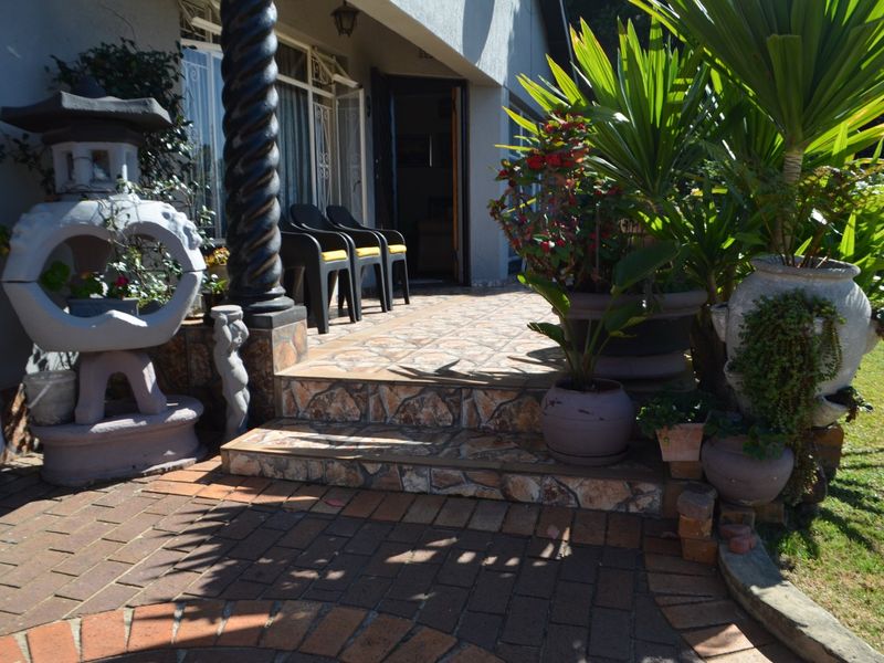 A covered patio area featuring decorative tiled steps, a stone pillar, and direct access to the home through sliding glass doors.