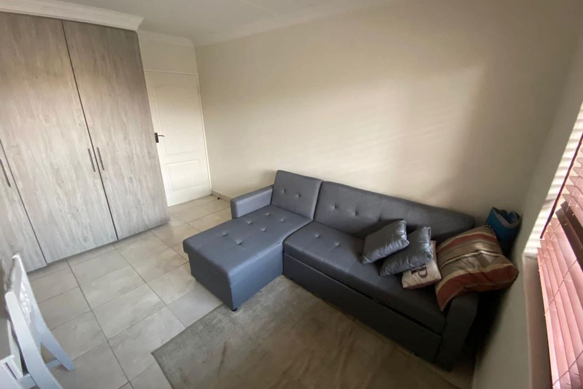A living area featuring tiled flooring, a built-in wardrobe, and neutral wall finishes, providing a functional and compact space.