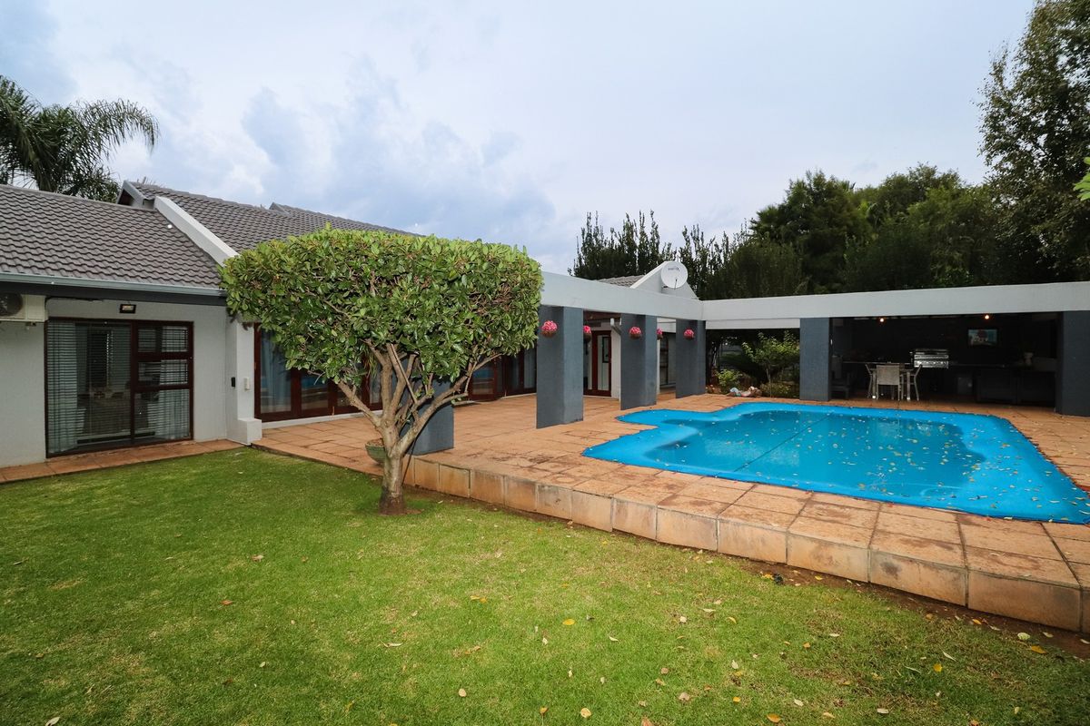 Rear exterior view featuring a swimming pool with cover, covered patio area, and landscaped garden space.