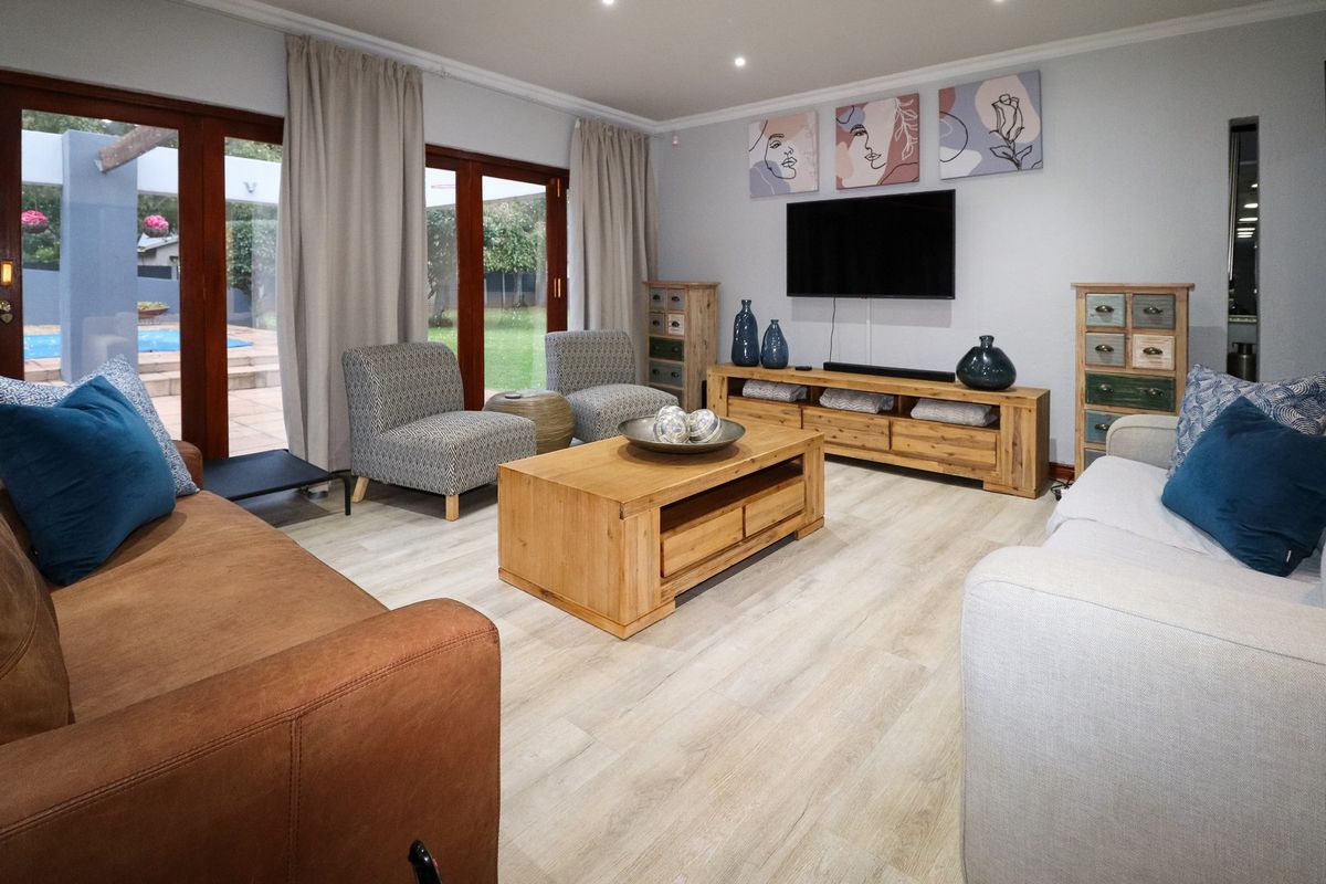 A bright and inviting living room featuring light wood-look flooring, recessed ceiling lighting, and large glass sliding doors providing direct access to the outdoor area.