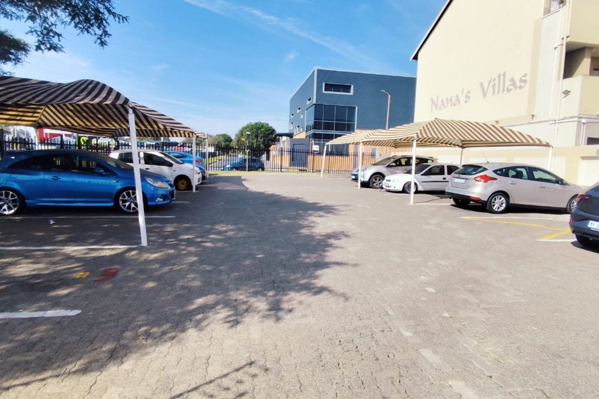 Exterior view of the apartment complex parking area featuring paved surfaces and covered parking bays for residents.