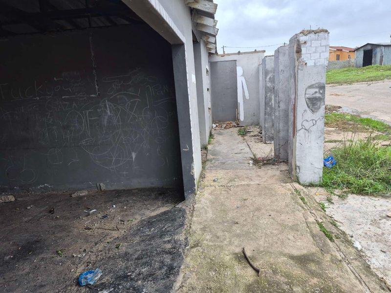 Exterior view of a commercial structure showing significant wear, graffiti, and exposed concrete elements requiring extensive maintenance and repair.
