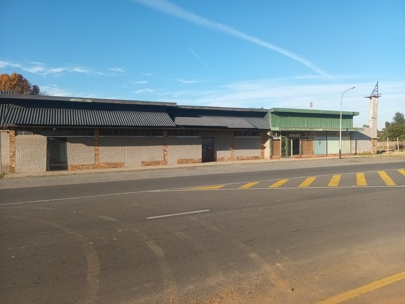 Street-facing commercial property featuring a long brick facade with corrugated metal roofing and integrated security gates.