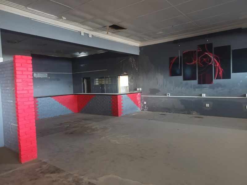 An empty commercial bar area featuring a built-in brick counter, requiring significant refurbishment of the walls, ceiling, and flooring to restore functionality.