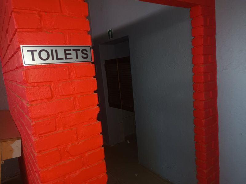 A commercial hallway entrance featuring painted brickwork and clear signage leading to the restroom facilities.