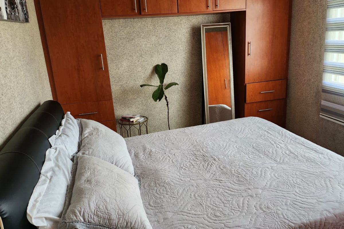 A bedroom featuring built-in wooden cabinetry and wardrobes, providing ample storage space, complemented by modern roller blinds on the window.