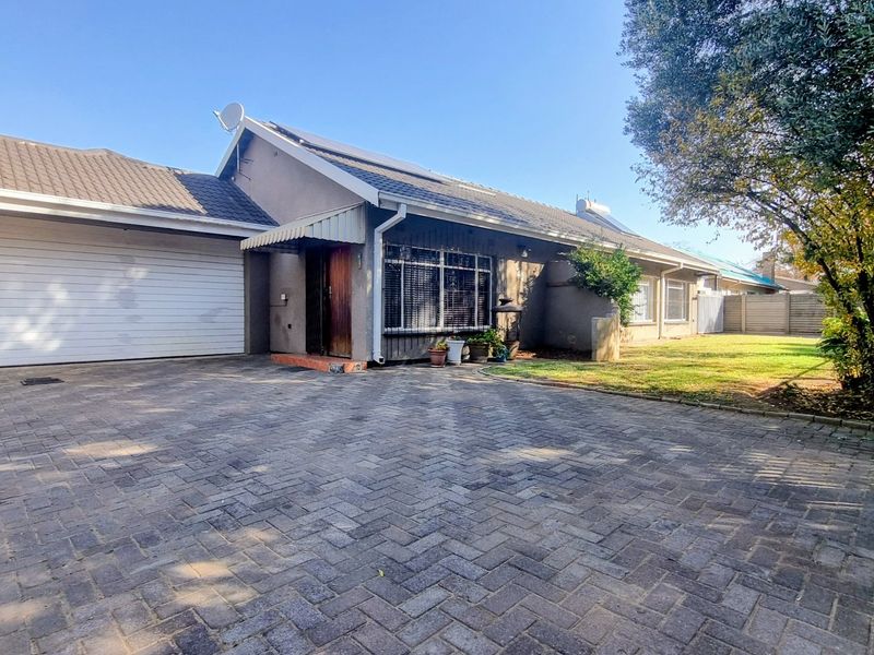 Front view of a single-story house featuring a paved driveway, double garage, and tiled roof with installed solar panels.