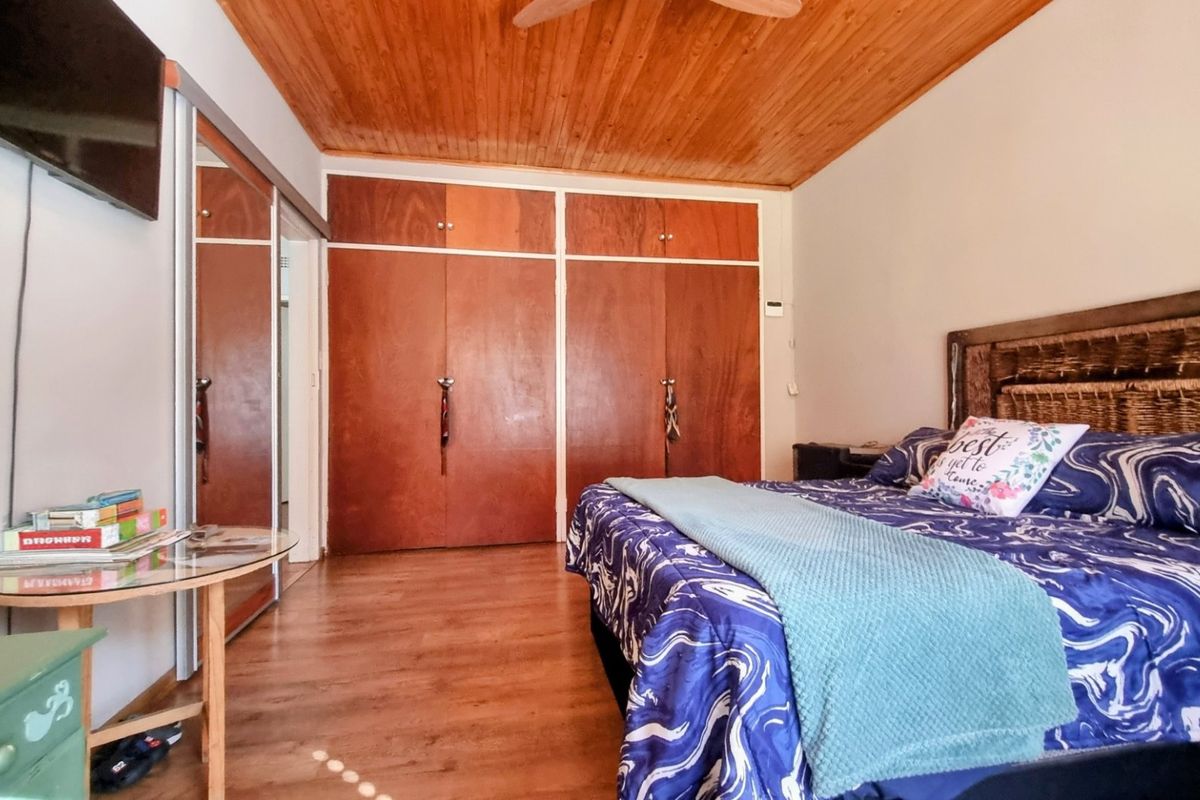 A bedroom featuring warm wooden ceiling paneling, built-in wooden cabinetry, and laminate flooring, offering a cozy and functional living space.