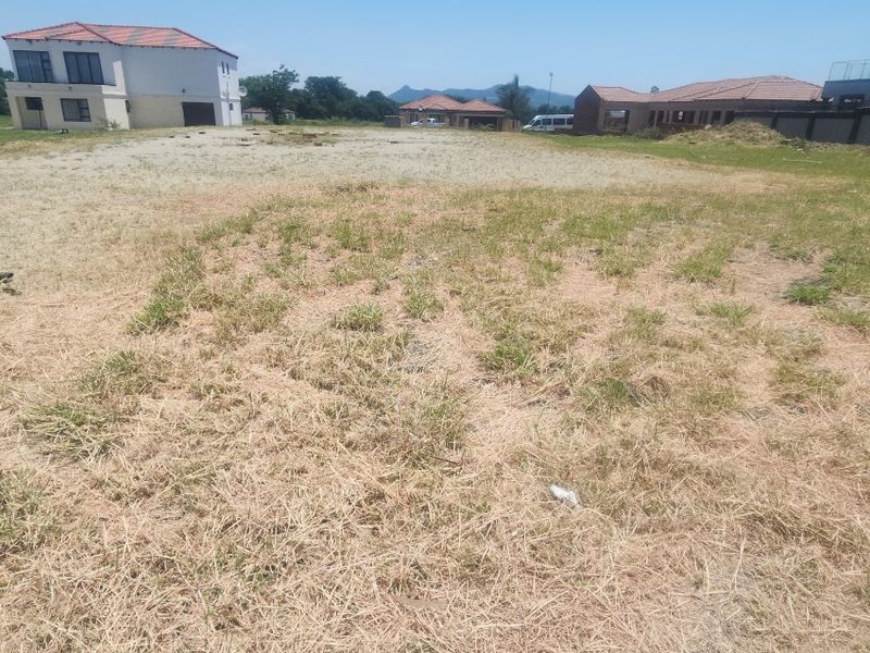 A view of a vacant residential plot of land with surrounding residential properties in a developed estate setting.