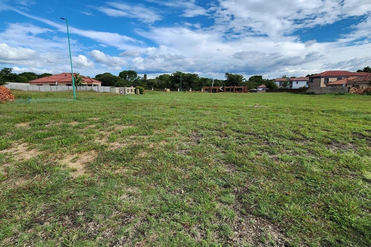 A wide-angle view of a vacant residential plot featuring a grass lawn and surrounding perimeter walls in a developed neighborhood.