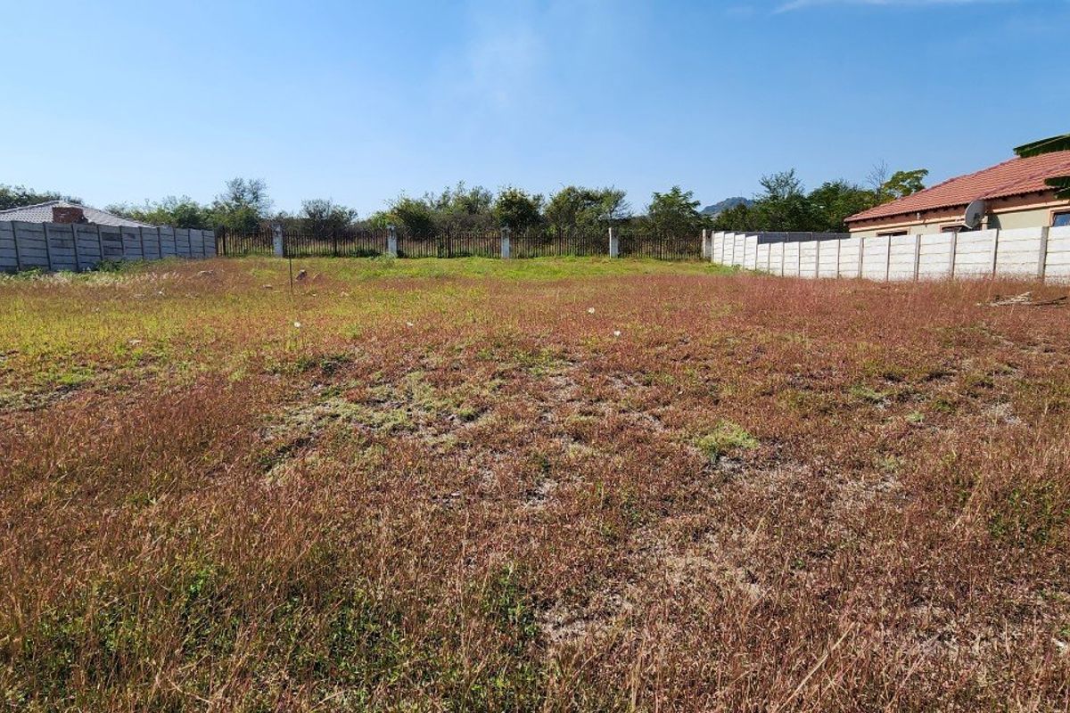 A vacant residential plot enclosed by precast concrete boundary walls and metal fencing, ready for development.