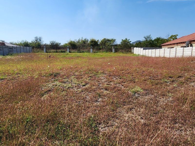 A vacant residential plot enclosed by precast concrete boundary walls and metal fencing, ready for development.