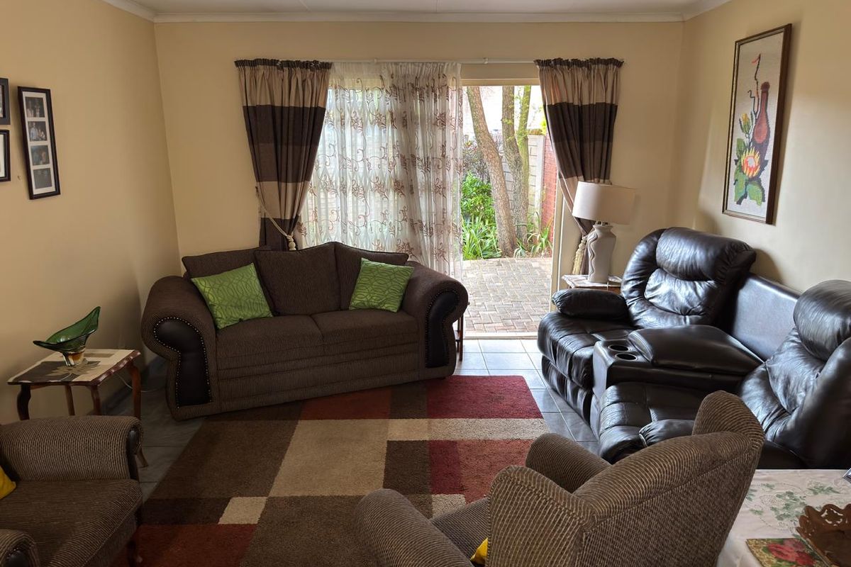 A comfortable living room featuring tiled flooring and a sliding glass door providing access to the outdoor patio area.