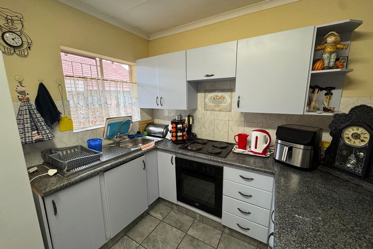 A functional kitchen featuring built-in cabinetry, granite countertops, a built-in oven with electric hob, and tiled flooring.