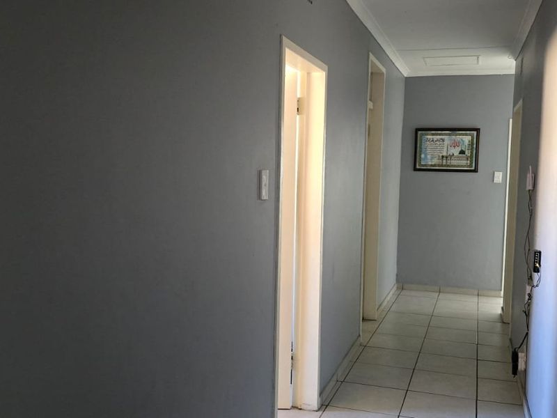 A clean, neutral-toned hallway featuring tiled flooring and access to multiple rooms, providing a functional transition space within the home.