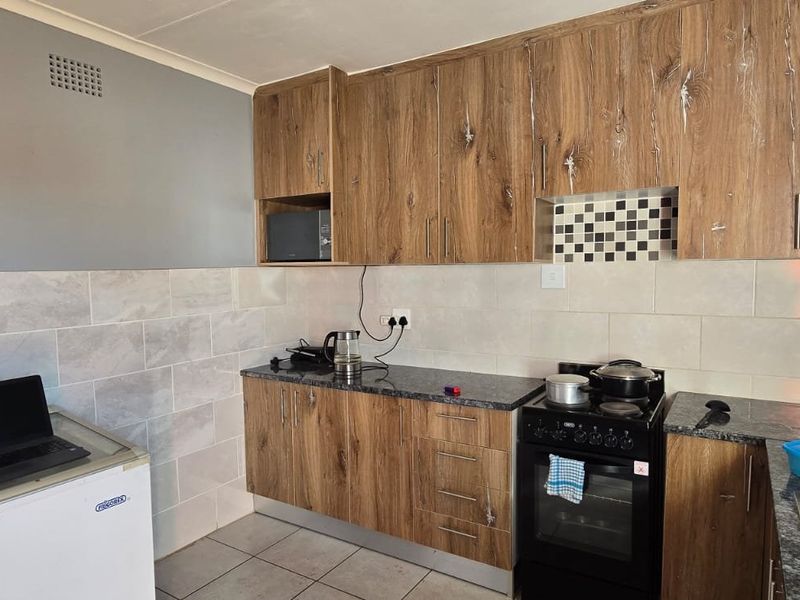 Functional kitchen featuring wood-look cabinetry, granite countertops, tiled backsplash, and a freestanding oven, providing a practical workspace.