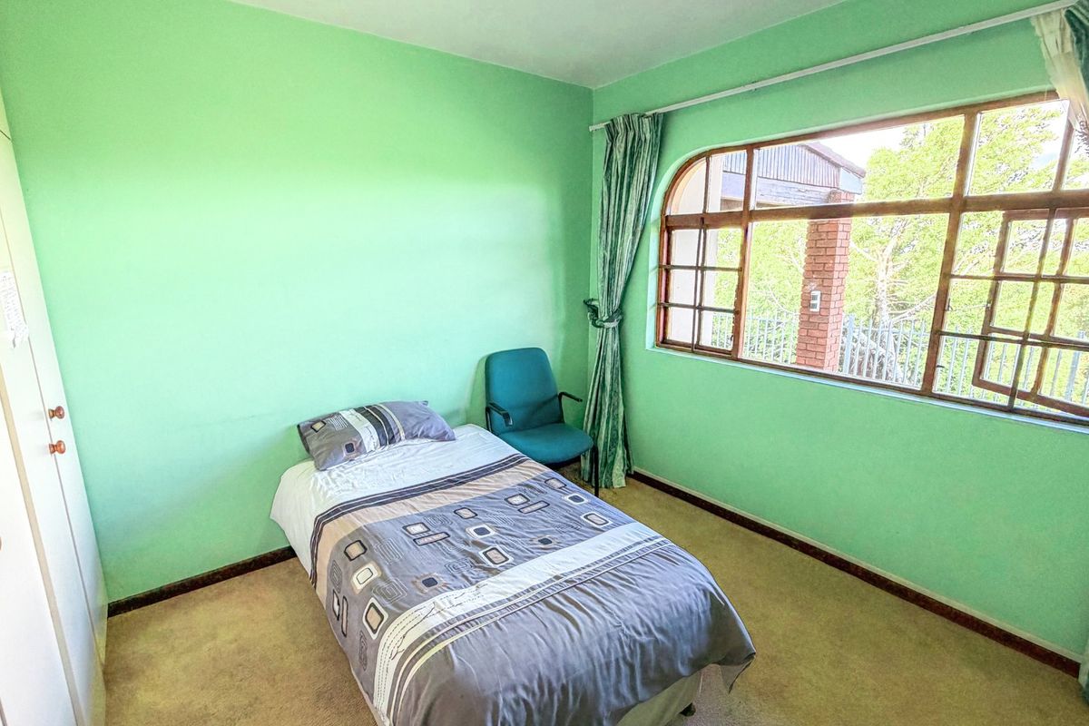A bedroom featuring built-in wardrobes, carpeted flooring, and a large arched window providing natural light.