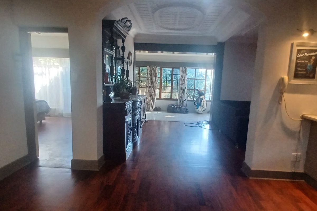 A living area featuring hardwood flooring, a built-in bar, and decorative ceiling molding, with an archway leading to an adjacent room.