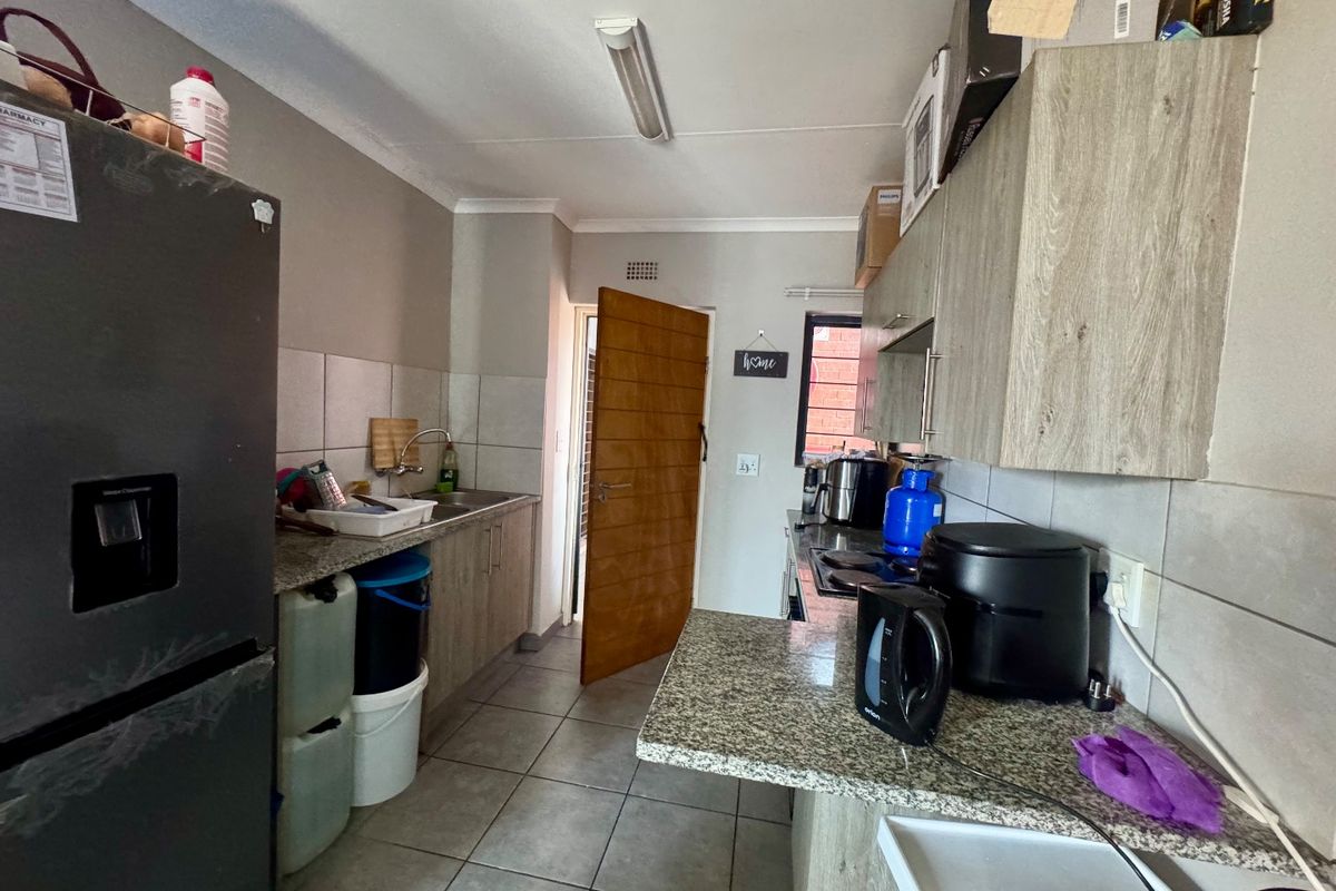 A functional kitchen featuring granite countertops, laminate cabinetry, tiled flooring, and a tiled backsplash, providing a practical workspace for daily cooking.