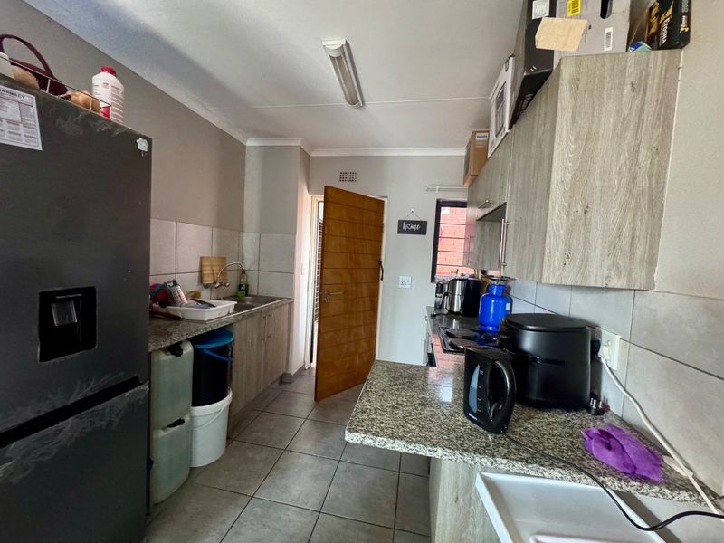 A functional kitchen featuring granite countertops, laminate cabinetry, tiled flooring, and a tiled backsplash, providing a practical workspace for daily cooking.