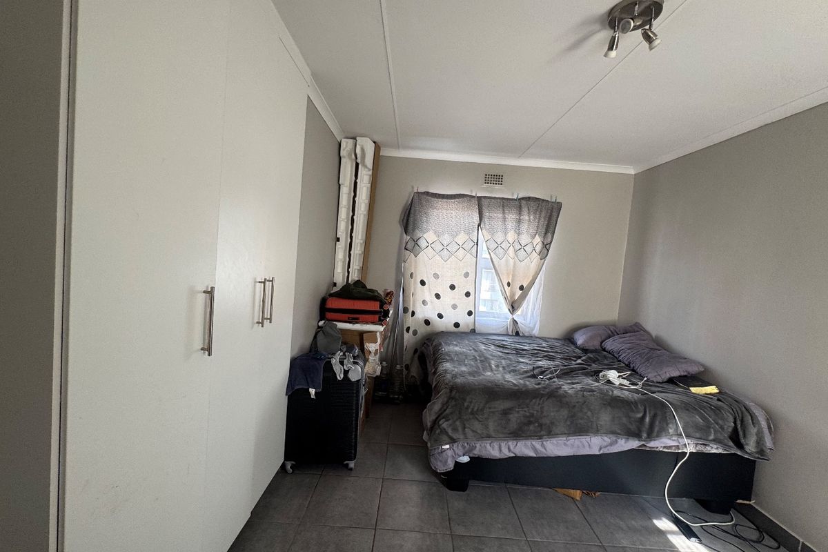 A bedroom featuring built-in cupboards, tiled flooring, and a ceiling-mounted light fixture.