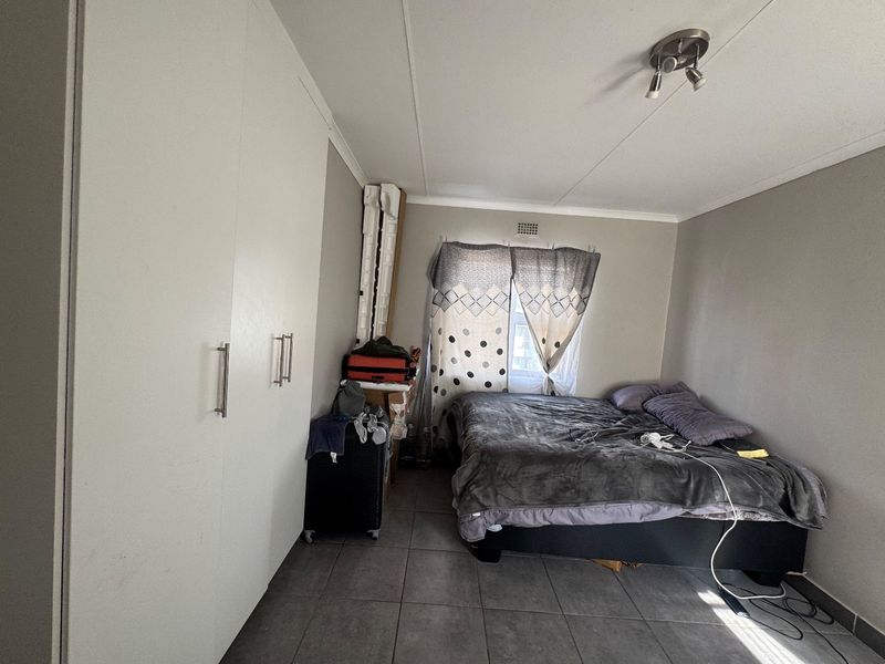 A bedroom featuring built-in cupboards, tiled flooring, and a ceiling-mounted light fixture.