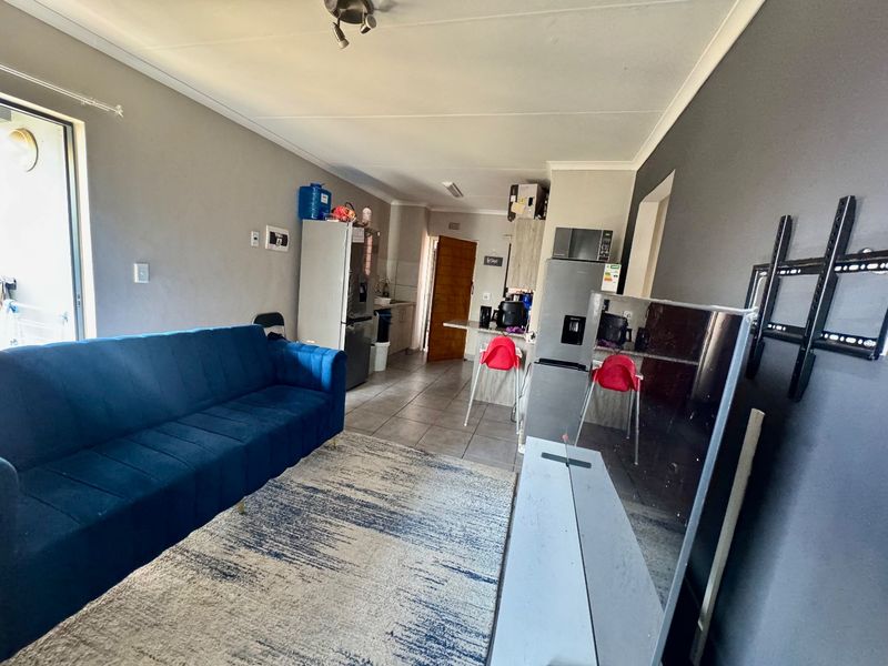 Open-plan living and kitchen area featuring tiled flooring, a breakfast counter, and direct access to an outdoor space via a sliding glass door.
