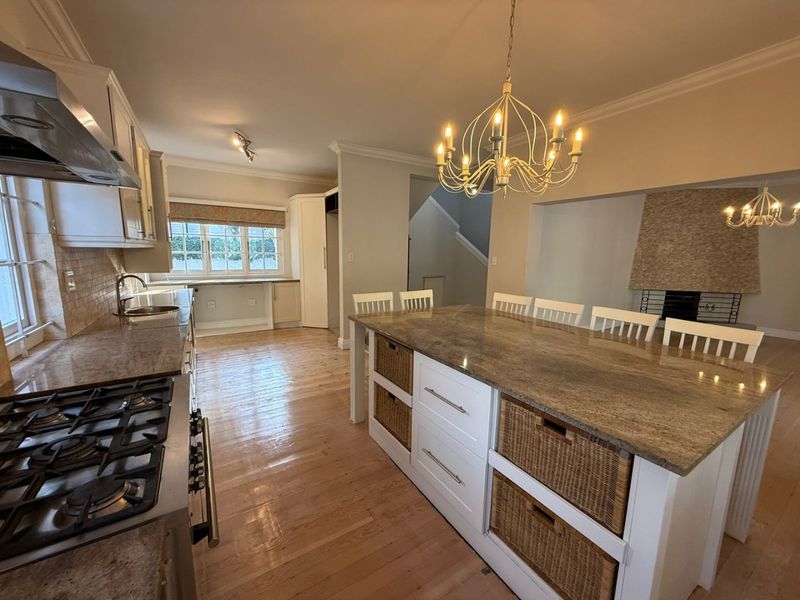 Spacious open-plan kitchen and dining area featuring a large central island with granite countertops, gas cooktop, and a cozy fireplace.