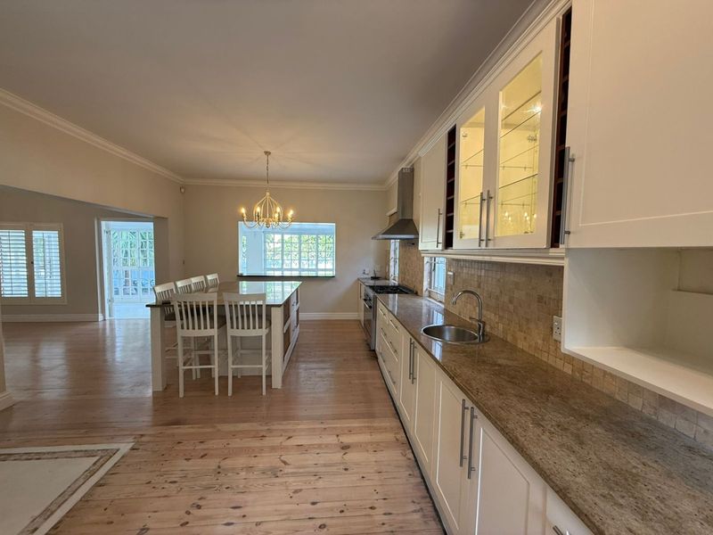 Spacious open-plan kitchen featuring granite countertops, ample cabinetry, integrated appliances, and hardwood flooring, flowing seamlessly into the dining and living areas.