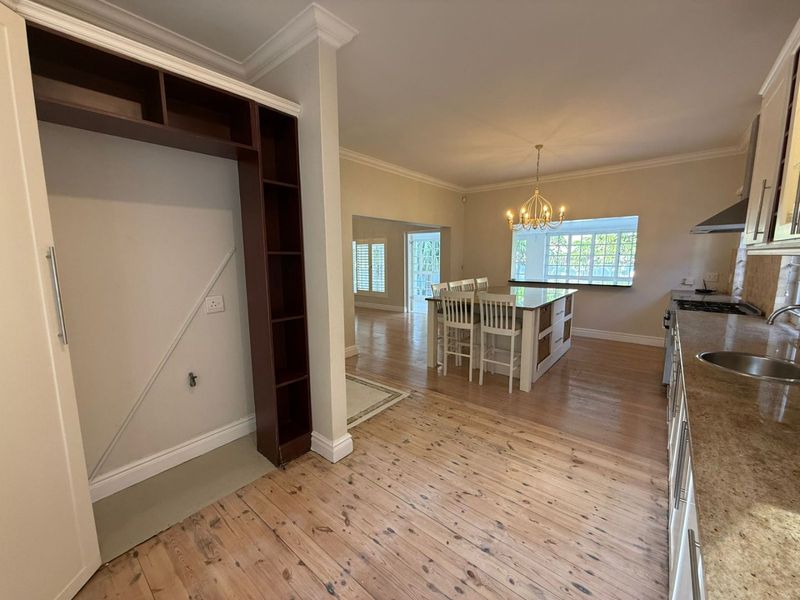 Spacious open-plan kitchen and dining area featuring timber flooring, granite countertops, a central island, and classic crown molding details.