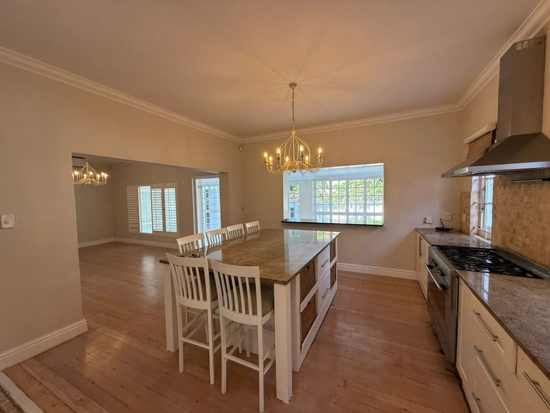 Spacious open-plan kitchen featuring a large granite island, stainless steel appliances, hardwood flooring, and seamless flow into the adjacent living area.